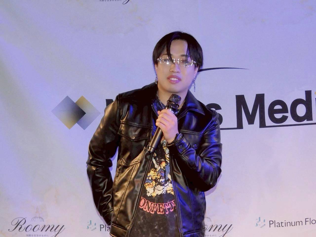 眼鏡をかけてマイクで語る前田健人